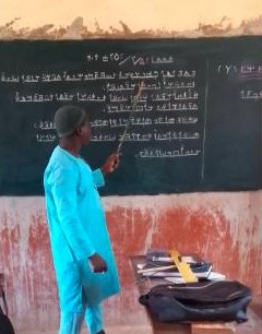 Un enseignant écrit en NÈNÈ au tableau devant une classe